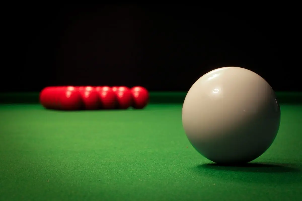 White cue ball and red snooker balls on green baize