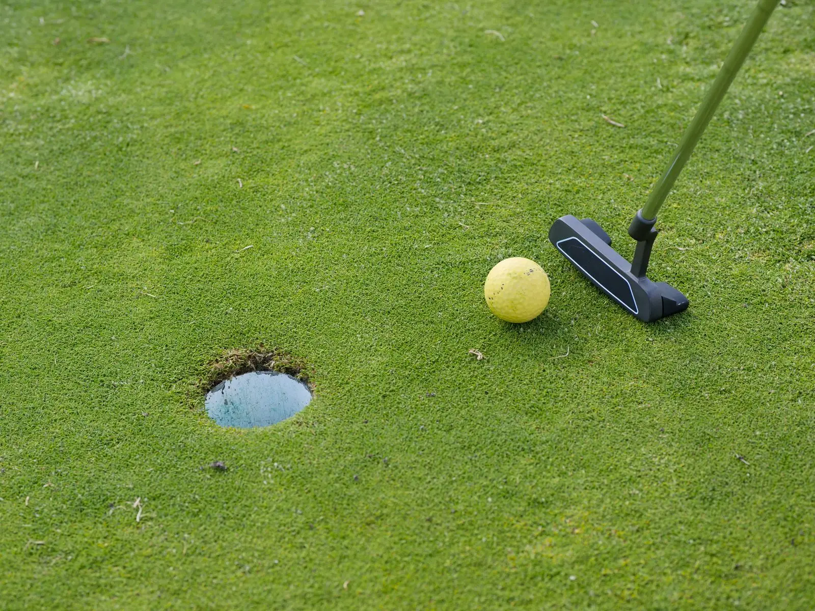 Putter and ball beside a golf hole