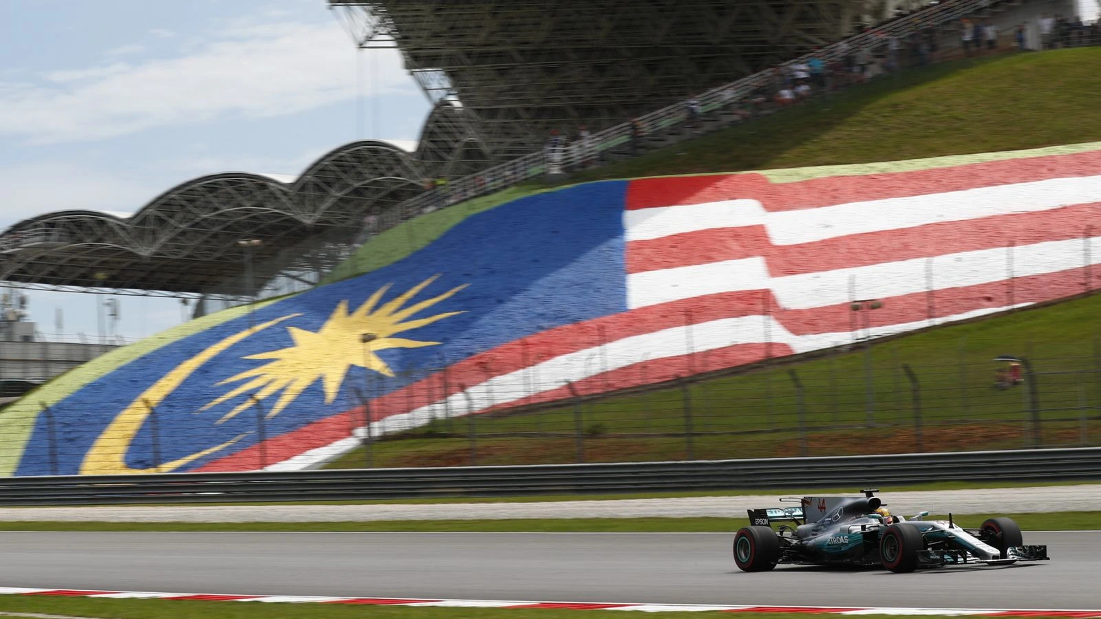 Formula 1 car races past the Malaysian flag at Sepang