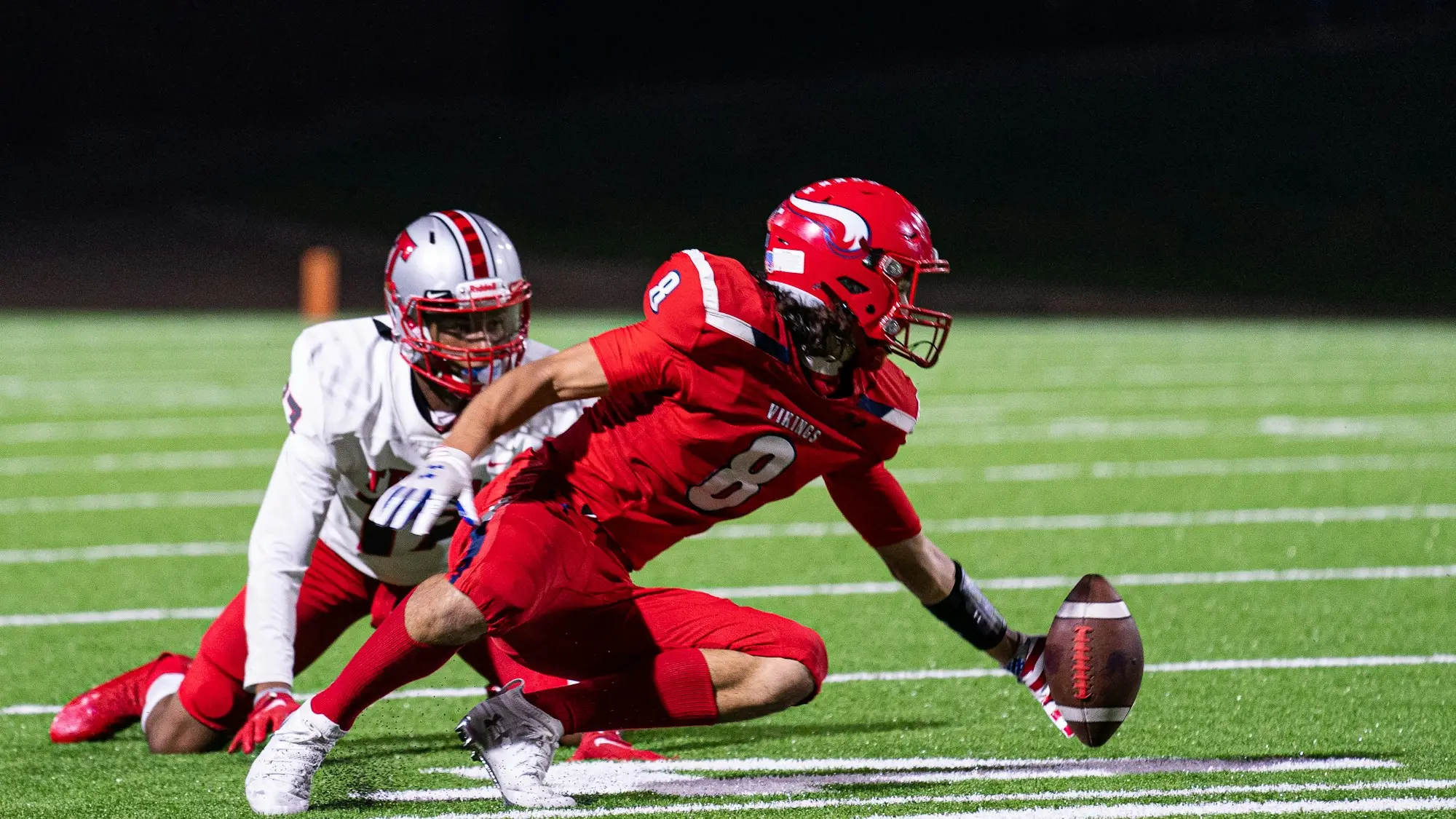 American football players contesting the ball on the turf