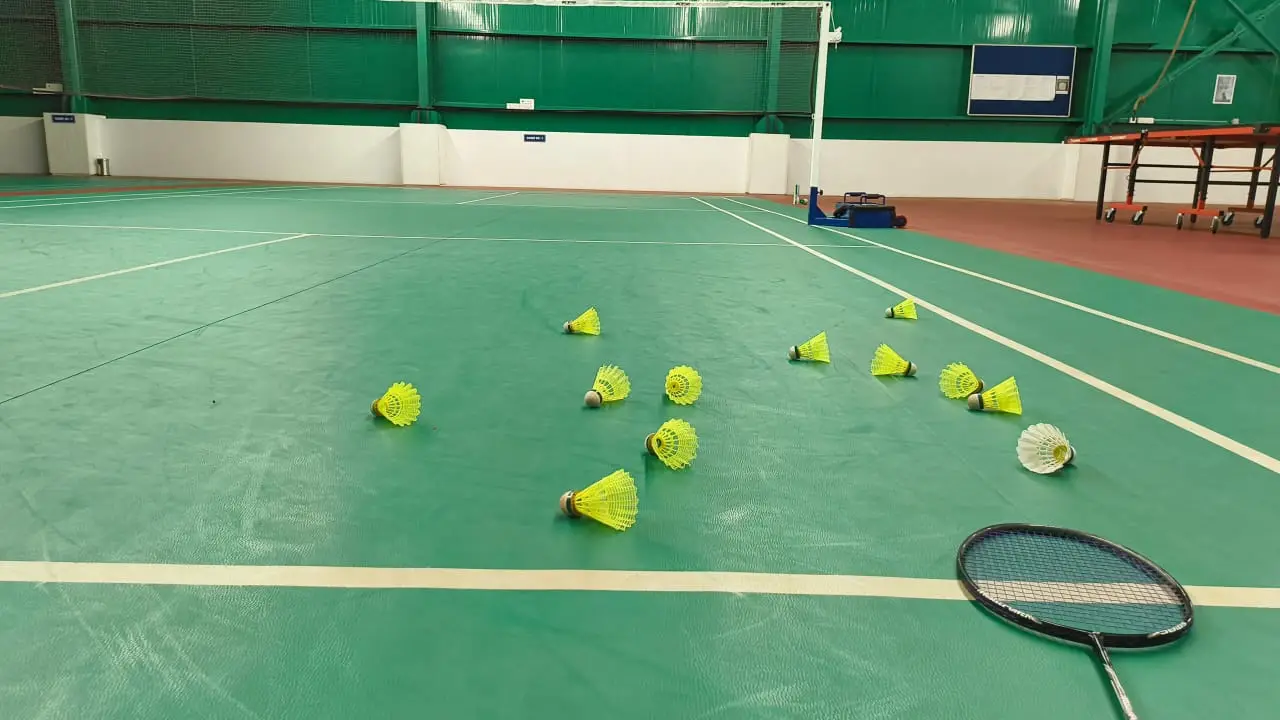 Badminton racket and shuttlecocks on an indoor court