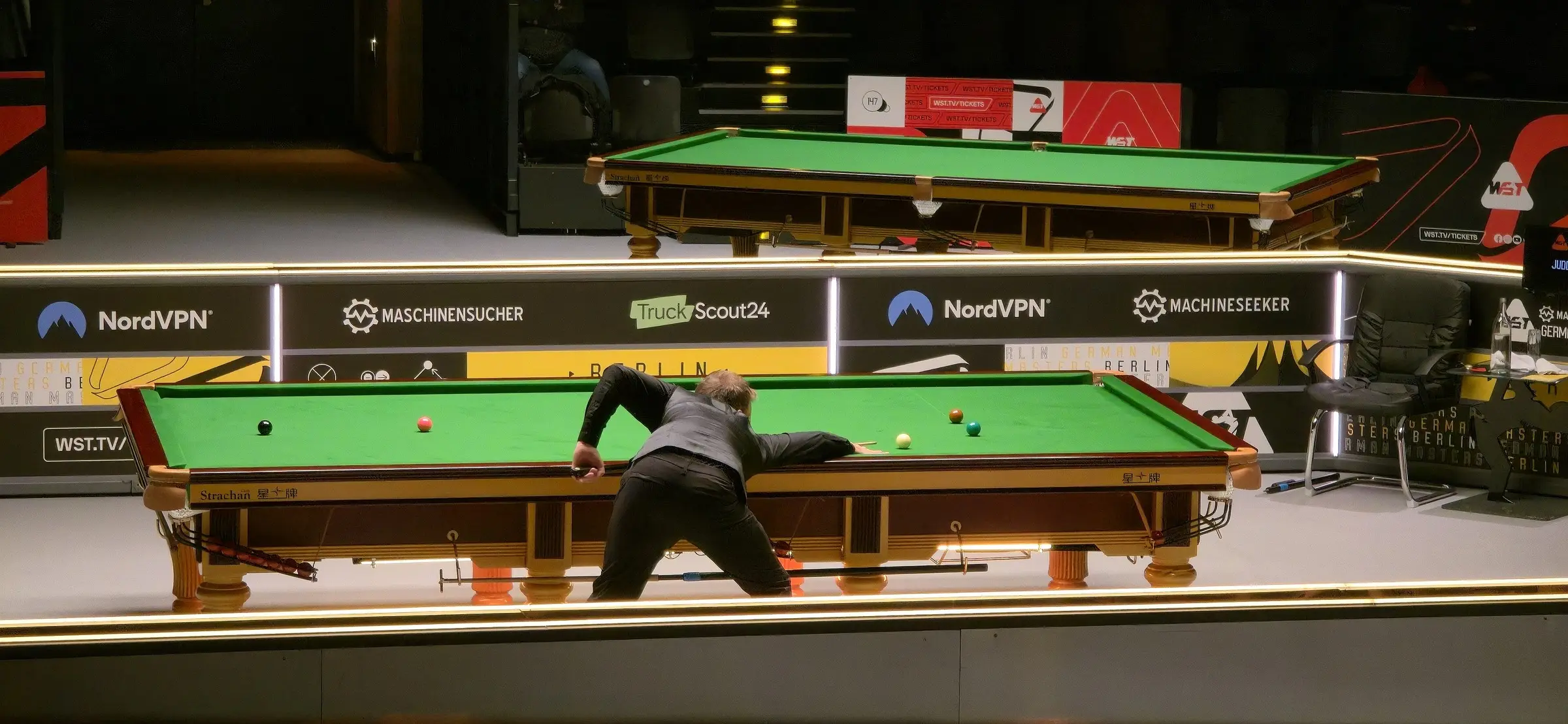 Judd Trump playing from a wide arena angle at the 2026 German Masters